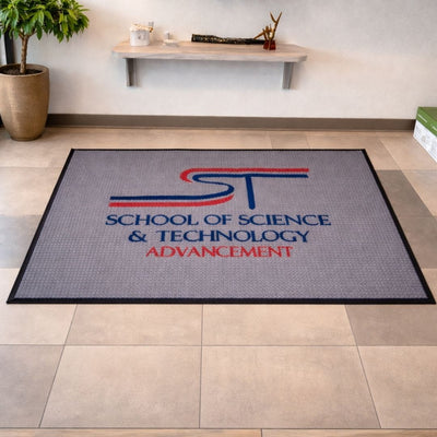 Gray doormat with 'School of Science & Technology Advancement' text and logo on a tiled floor.