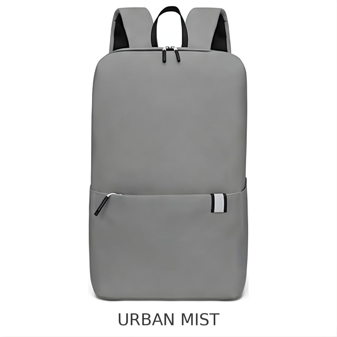 A gray backpack shown from the front on a white background, with the text 'URBAN MIST' underneath. The backpack has black shoulder straps, a black top handle, and a front zippered pocket with a small white accent tab.