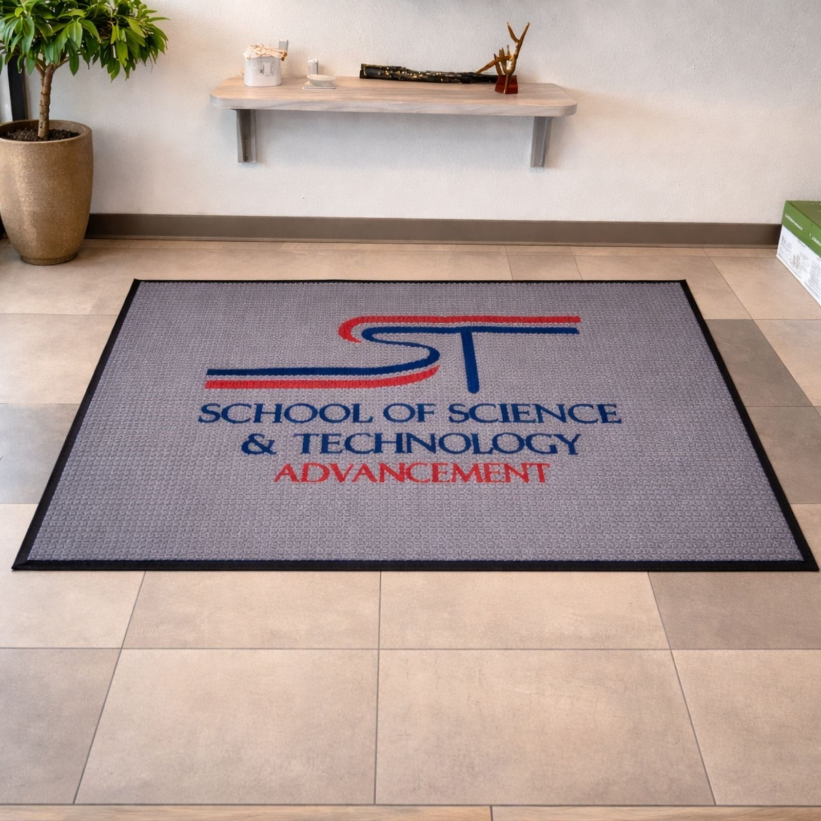Two branded mats on a tiled floor with a counter and sunflowers in the background.